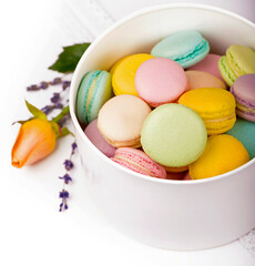 Many delicious colorful macarons in box on white background