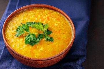 Bowl of lentil soup on a blue linen napkin. Red lentil soup with fresh parsley. Traditional middle eastern food. Close up