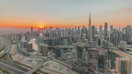 Naklejka na ściany i meble Skyline with modern architecture of Dubai business bay towers at sunset timelapse. Aerial view