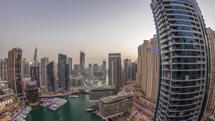 Fototapeta premium Aerial view to Dubai marina skyscrapers around canal with floating boats day to night timelapse