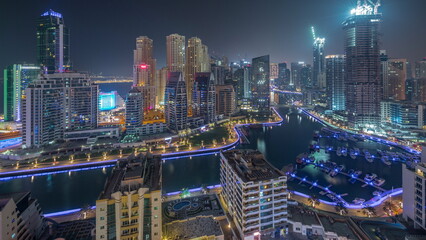 Fototapeta na wymiar Dubai Marina with several boat and yachts parked in harbor and skyscrapers around canal aerial all night timelapse.