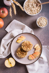 Appetizing crumble of apples and oatmeal on a plate and fruits on the table. Top and vertical view