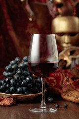 Red wine, grapes, and vintage carnival masks.