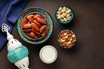 Ramadan Kareem food and drinks. Date fruits, nuts and milk on a dark background. Ramadan kareem fasting month concept. Top view