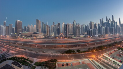 Naklejka na ściany i meble Panoraama of Dubai Marina skyscrapers and Sheikh Zayed road with metro railway aerial night to day timelapse, United Arab Emirates