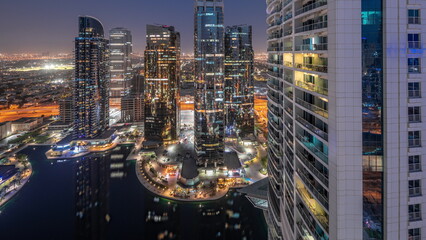 Obraz premium Tall residential buildings at JLT aerial day to night timelapse, part of the Dubai multi commodities centre mixed-use district.