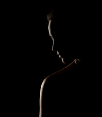 Sensual pprofile silhouette of beautiful woman in backlight on a black background