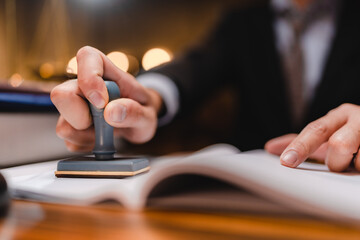 businessman or lawyer put a success stamp on legal deal contract in office, approved on certificate document public paper agreements at desk of notary or business people work to making a signs permit