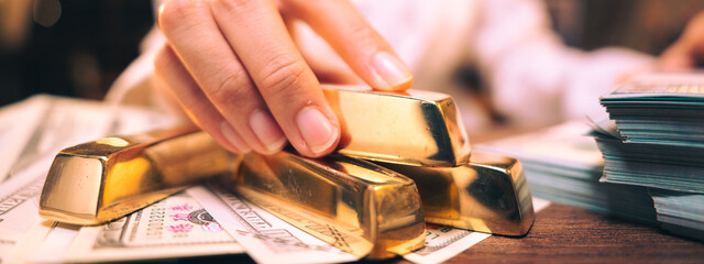 The hand holding the precious gold bar shows the success of the finance business and the economy of...