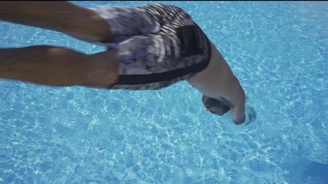 Man jumping head to the pool in slow motion.