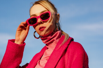 Fashionable confident blonde woman wearing trendy fuchsia color rectangular sunglasses, pink...