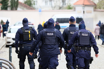 Policjanci prewencji w mundurach idą na akcję w mieście. 