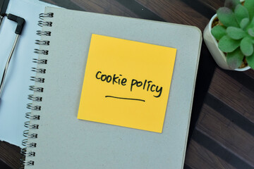 Concept of Cookie Policy write on sticky notes isolated on Wooden Table.