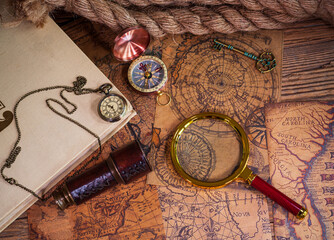 Old items, book, pocket watch, compass, magnifying glass, spyglass, old maps, thick rope in flat lay shot