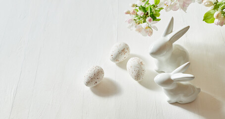 Holiday composition with spring flowers and easter eggs, white bunny on a light background.  Happy easter concept with copy space