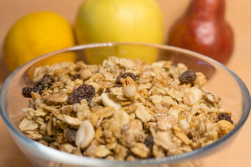 muesli in a glass plate in the background red pear, yellow block, lemon