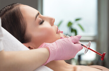 Cosmetologist does injections for lips augmentation and anti wrinkle in the nasolabial folds of a...