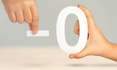 Minus zero. Numeral zero and minus symbol in a hand close-up on a light gray background. The...