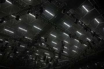 Dark background, ceiling light equipment, light black trusses.	