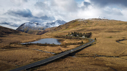 Drone shot of a lake and curving mountain road approaching Mount Snowdon, Wales