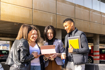 portrait of 4 business people of mixed ethnicity working together with a tablet in the street. Work meeting