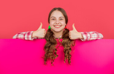 happy child behind blank pink paper with copy space for advertisement. thumb up