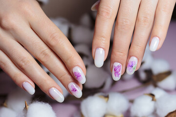 Obraz na płótnie Canvas Beautiful manicure with nail design. Female hands on fluffy cotton flowers.