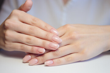 Gentle nude manicure on her nails. Classic bridal nail design.