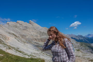 Portrait of young woman with long hair. Scenic landscape on the nature, Mount Latemar, Trentino, Italy. Traveling photography and outdoor sport activity concept