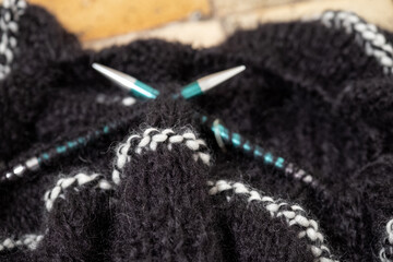 Black mohair yarn chunky sweater in the process of being knitted. Photograph shows textured...
