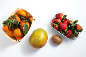 Fresh fruits mango, strawberries tangerines, kiwi on a white background. Top view, flat lay