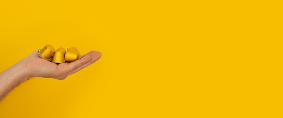 Coffee capsules in the female palm on a yellow background. Banner