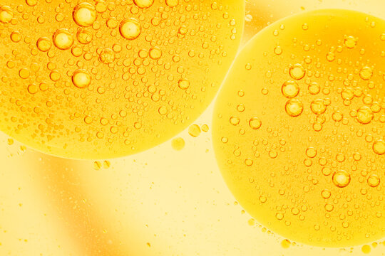 Beautiful cosmetic background. Golden yellow abstract oil bubbles or face serum background. Squalene oil and water bubbles macro photography.