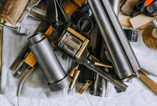 Retro weapons, a rifle with ammunition, a revolver with cartridges, parts and accessories close-up lie on the table. Close-up photo, the concept of a variety of firearms.