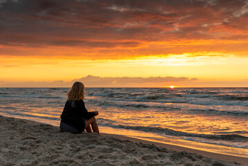 Dziewczyna oglądająca zachód słońca nad Bałtykiem  / A girl watching the sunset over the...