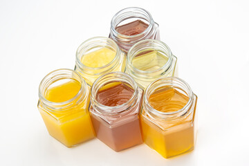 jars with different types and colors of honey on a white background. organic vitamin food