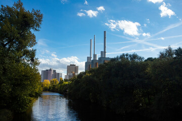 Naklejka premium Hannover, Germany - October 16, 2022. Beautiful Ihme river with trees and in the background the heating plant with the three towers