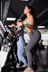 Fototapeta na wymiar Young fitness woman in sportswear doing cardio training on ellipsoid in gym