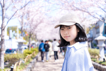 桜並木を観光する若い女性