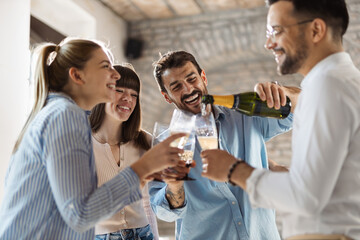 Young business colleagues pouring champagne during a party in the office