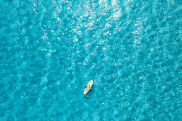 Aerial view of with man on sup board in blue sea at summer sunny day. Man on floating canoe in...