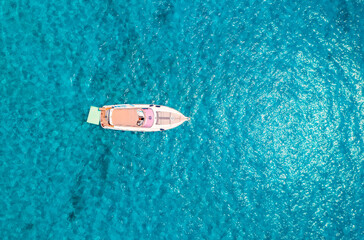 Aerial view of beautiful luxury yacht in blue sea in summer sunny day. Sardinia, Italy. Top drone view of speed boat, sea coast, transparent azure water. Travel. Tropical landscape. Yachting. Seascape