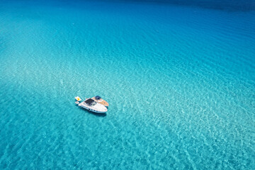 Aerial view of beautiful luxury yacht and boat in blue sea at sunny day in summer. Sardinia island, Italy. Top drone view of speed boat, ocean, azure clear water. Travel. Tropical landscape. Yachting