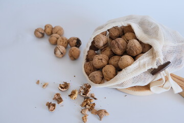Cotton mesh bag with walnuts and walnut kernels, shells  on a white background.