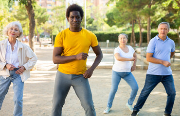 Group of multiracial friends, various ages getting together outdoors and dancing simple moves on a sunny day in autumn