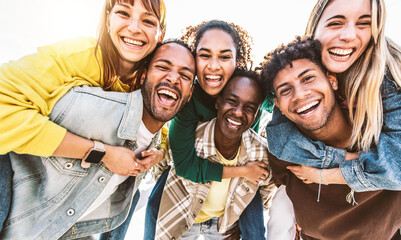 Multiracial young people smiling at camera outside - Group of best friends having fun hanging out...