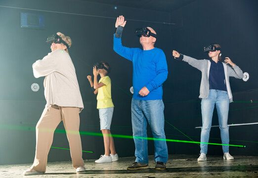 Family of four people, grandparents and grandchildren, playing VR games together.
