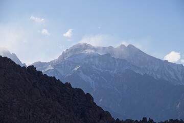 Clouds drift over the Sierra Nevada Mountains, which were dusted in snow, as seen from the Eastern Sierra
