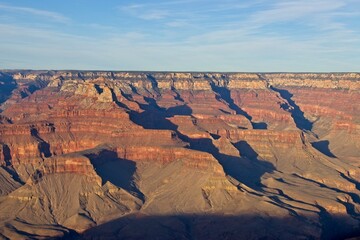 Bright desert sunlight shines down on the Grand Canyon, casting shadows on every crease and layer...