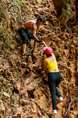 Asian family mother and son helping each other during climbing on rocky mountain together at tropical island. Man and woman enjoy outdoor active lifestyle and extreme sport climbing on summer vacation